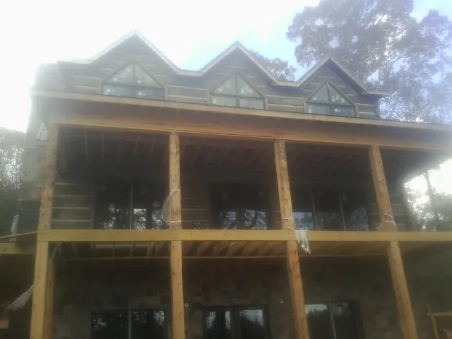 Dormers and porch framing on a large log home under construction — Roof Coating work by our crew in Olanta
