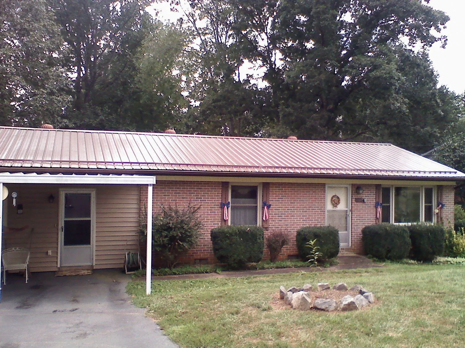 Bronze metal roof and carport on a brick ranch home — Roof Repair work by our crew in Olanta