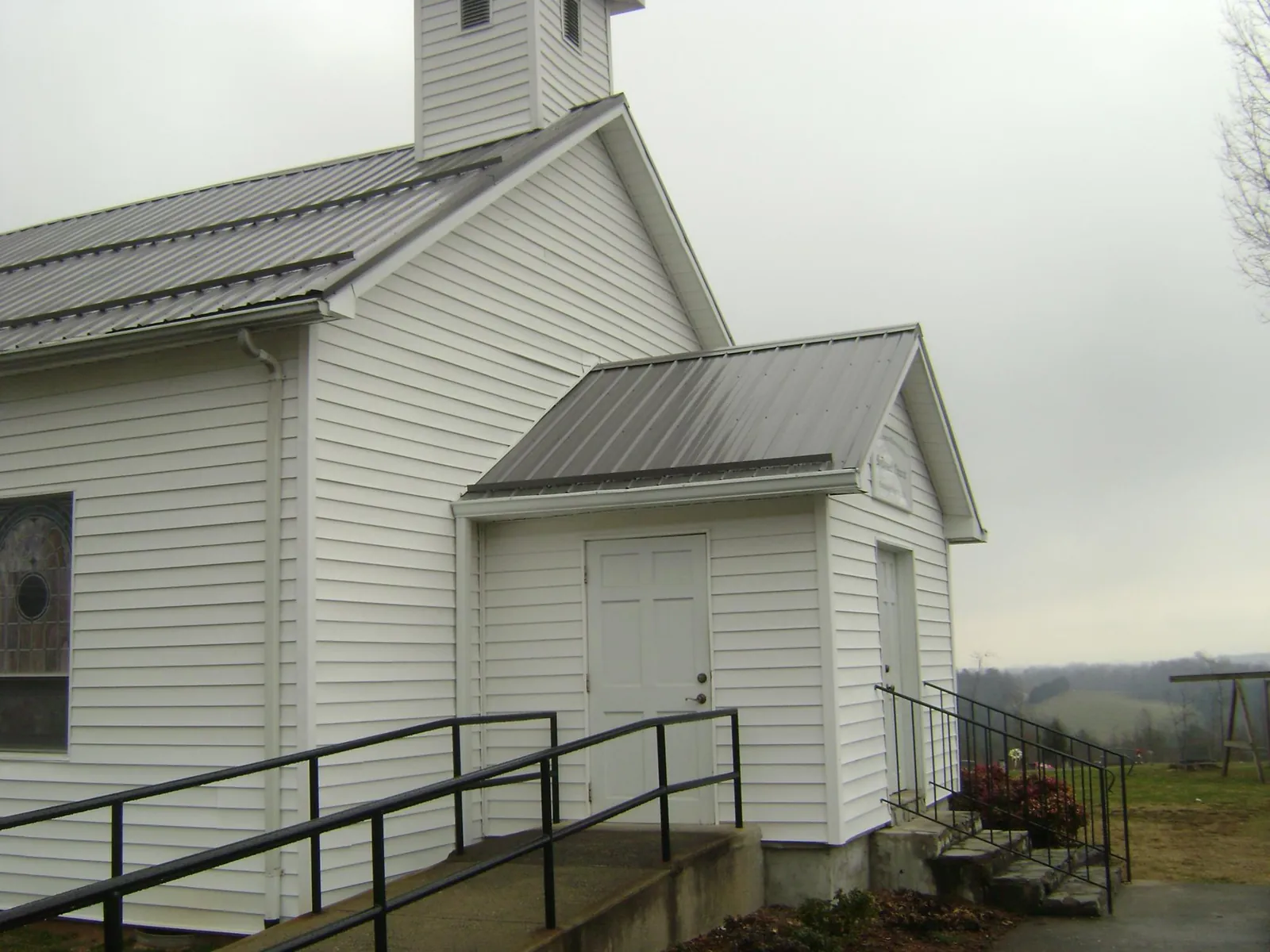 Gray metal roof on a white clapboard church with a steeple in Olanta