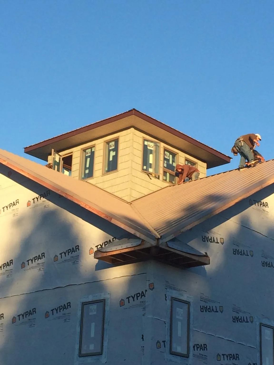 Roofers working around a rooftop cupola on a new metal roof at sunset — Roof Waterproofing in Olanta by Roofing Brothers